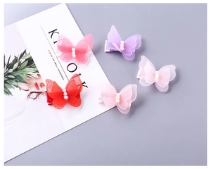 Détail de quatre barrettes papillon avec ailes en tulle fin et perles élégantes au centre