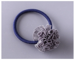 Détail d'une fleur en tulle gris sur un élastique à cheveux bleu foncé pour enfant