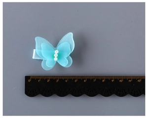 Détail du clip papillon en tulle bleu clair avec perles, montrant une largeur de 4,5 cm