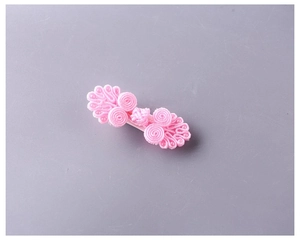 Dettaglio di un fermaglio per capelli rosa a nodo cinese fatto a mano con perline
