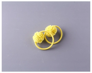 Détail de deux élastiques à cheveux pompons jaunes en tissu de tulle doux superposé