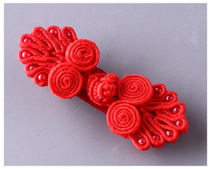 Dettaglio di un bottone cinese rosso in seta intrecciata con perline decorative