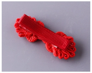 Dettaglio di fermaglio per capelli rosso intrecciato a mano con fodera in tessuto