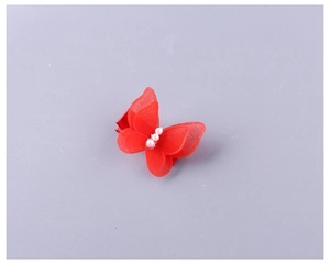 Détail d'une pince à cheveux papillon rouge en tulle avec perles et ruban assorti