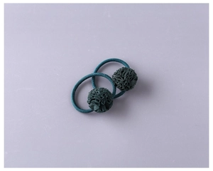 Détail d'élastiques à cheveux tricotés vert foncé avec des pompons floraux faits main