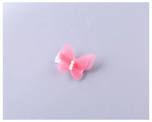 Vue détaillée d'une pince à cheveux papillon rose en tulle avec des perles blanches