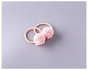 Gros plan d'une paire d'élastiques à cheveux à pompons en maille rose pour filles