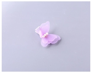 Gros plan détaillé d'une pince à cheveux papillon en tulle violet avec trois perles blanches