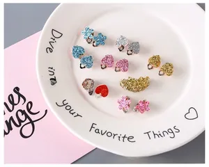 Macro shot of colorful glitter heart and flower clip-on earrings for girls without piercings