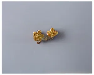Detail of glittery gold flower clip-on earrings for girls with silver metal backs