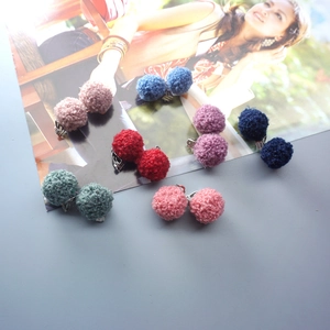 Close-up of fluffy colorful plush ball clip-on earrings in multiple pastel shades