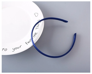 Detail view of a 1cm navy blue satin covered plastic headband on a white ceramic tray