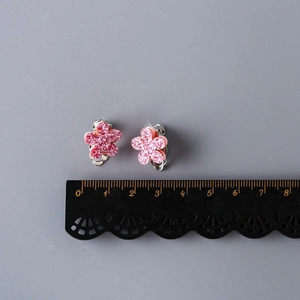 Pink glitter flower clip-on earrings for girls without piercings on a grey background