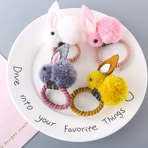 Close-up of fluffy bunny hair ties in white, pink, grey and yellow on a ceramic tray
