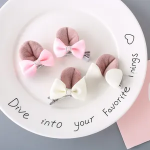 Set of 4 cute glitter rabbit ear hair clips with pink and white bows on a ceramic plate