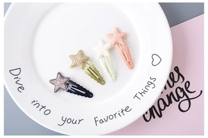 Macro view of four glittery star-shaped hair clips for girls in a ceramic bowl