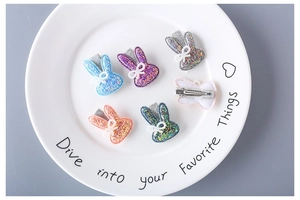 Detailed view of glittery rabbit hair clips in five colors with lace bows and duckbill clips