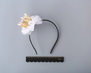 Detail of a sparkling gold glitter crown headband with white tulle on a black band