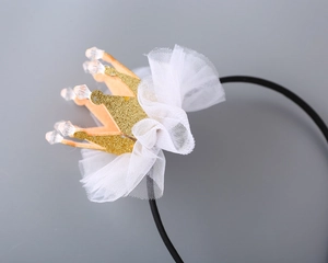 Detailed macro view of a glittery golden crown headband with white tulle and crystal beads