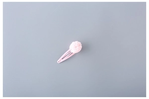 Close-up of a pink fabric flower ball on a matte lacquered snap hair clip for girls