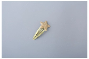 Close-up of sparkling gold star hair clip with glitter finish and metallic wave base