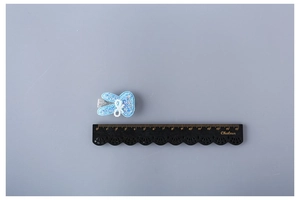 Detailed close-up of a blue glitter bunny hair clip next to a measurement ruler for scale