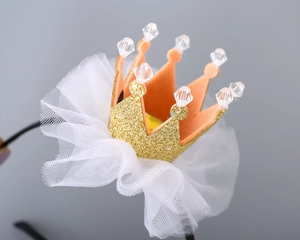 Close-up of a sparkling gold glitter crown headband with white tulle and crystal beads