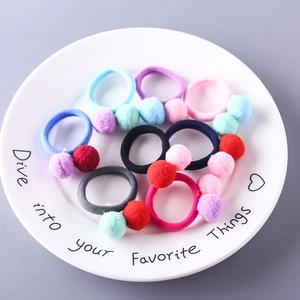 Gros plan sur des chouchous à pompons colorés dans un bol en céramique décoratif