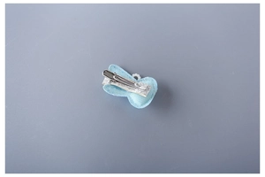 Detail view of the silver alligator clip on the back of a light blue glitter bow hairclip