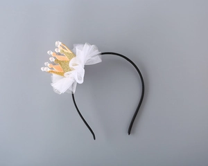 Close-up of a sparkling gold crown headband with white lace ruffles and clear crystal beads