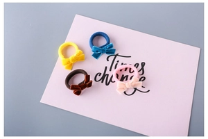 Close-up of four velvet bow hair ties in yellow, blue, coffee and pink on a gift card
