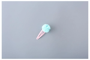 Detailed view of pink metal BB clip with a soft light blue mesh pom-pom for kids hair