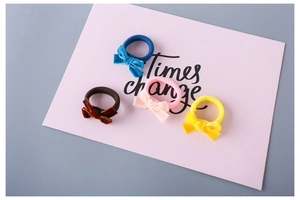Close-up of four colorful velvet bow hair ties in navy blue, brown, pink, and yellow