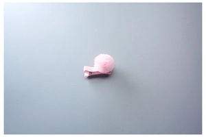 Détail d'une pince à cheveux à pompon en tulle rose clair avec base en ruban