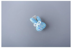 Close-up of a blue glittery rabbit hair clip with a pearl bow detail and metal clip