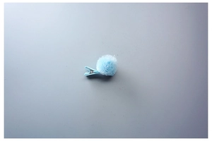 Détail d'une pince à cheveux boule en peluche bleu clair avec clip de sécurité en tissu