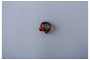Close-up of a brown velvet bow hair tie with a high-elasticity braided rope on grey surface