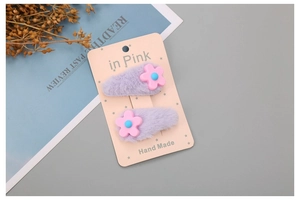 Detail von lavendelfarbenen Webpelz-Haarklammern mit Harzblüten auf rosa Displaykarte