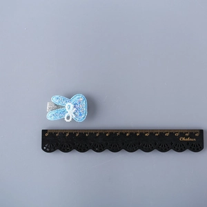 Glittery blue rabbit hair clip for girls with pearl bow accent on grey background