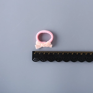 Pink velvet bow elastic hair tie for girls on a gray background with measurement scale