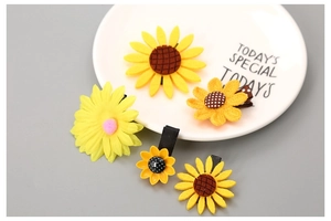 Close-up of five sunflower hair clips in yellow felt and mesh on a ceramic plate