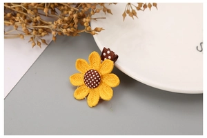 Detail of handcrafted woven sunflower hair clip with yellow petals and polka dot base