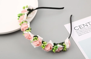 Dettaglio del cerchietto con rose rosa e bianche e bacche verdi su sfondo minimalista