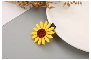 Detail of yellow sunflower hair clip with felt petals on a white porcelain plate