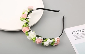 Dettaglio del cerchietto con rose finte rosa e bianche e piccoli boccioli verdi