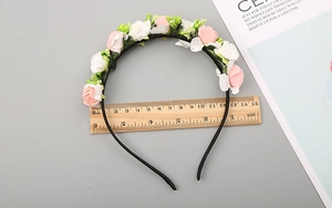 Dettaglio della fascia per capelli con fiori rosa e bianchi larga 13-14 cm su un righello