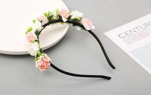 Dettaglio di rose in schiuma PE rosa e bianche su un cerchietto nero per capelli