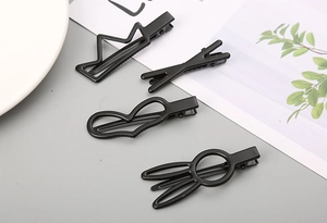 Détail de 4 barrettes en métal noir mat aux formes de couronne, de cœur et de lapin