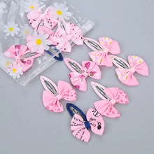 Flat lay of diverse pink bow hair clips with floral and strawberry patterns in packaging