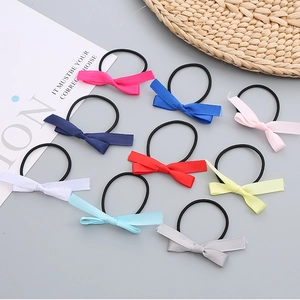 Detailed set of nine colorful silk bow tie hair elastics arranged on a grey background